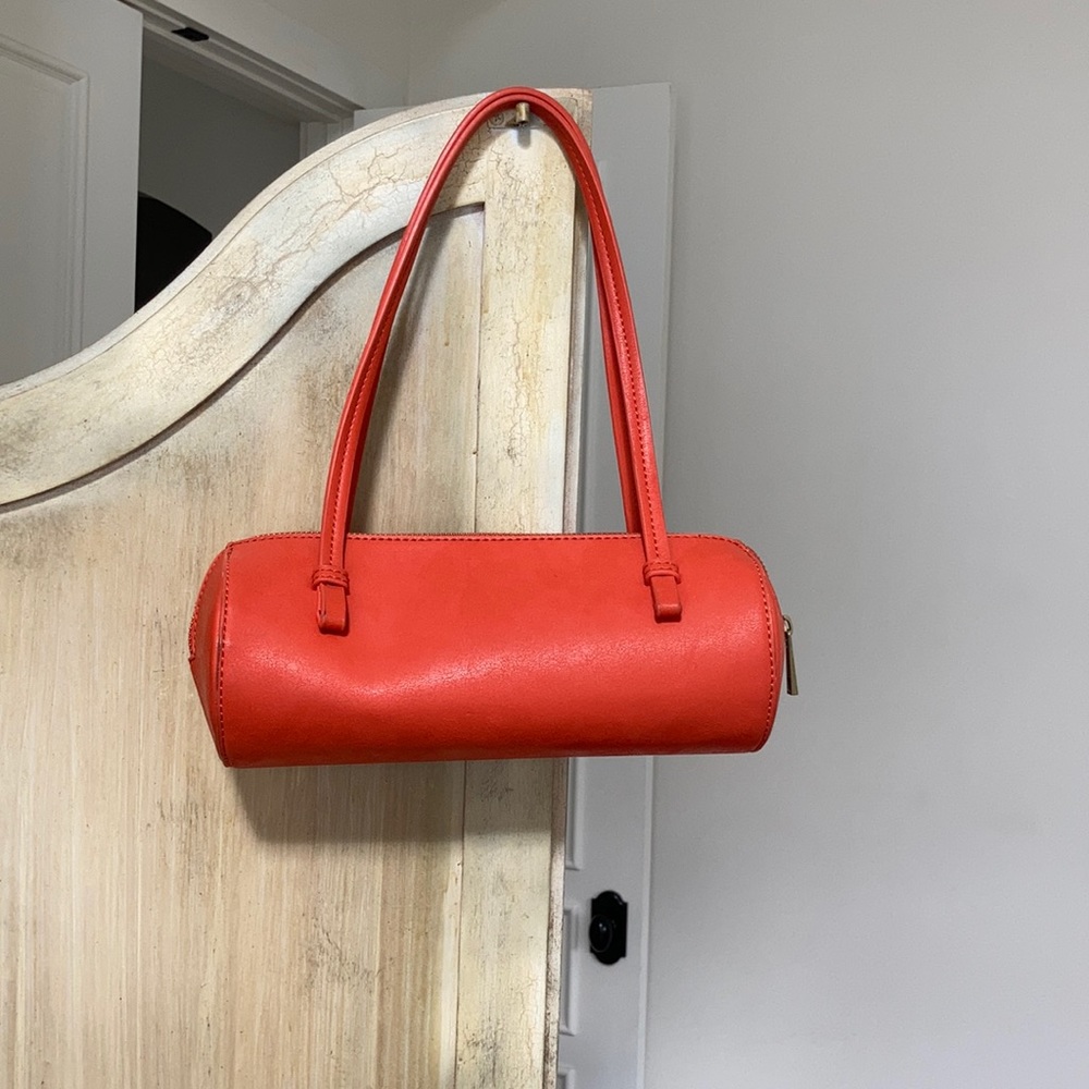 Orange leather shoulder barrel bag zip closer.